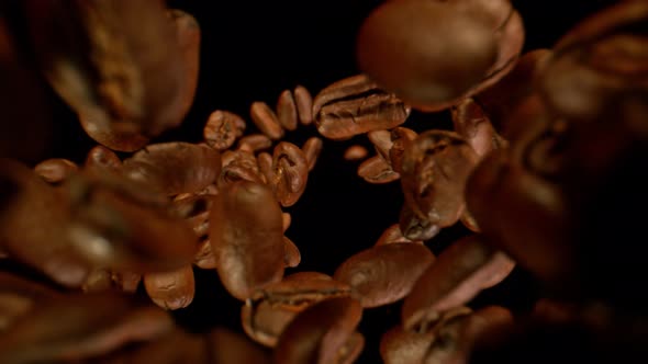 Super Slow Motion Detail Shot of Coffee Beans Falling Down on Black Background at 1000Fps alt