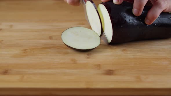 Slicing A Piece Of Seedless Eggplant With A Stainless Knife - close up alt