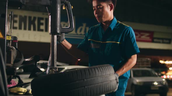 Professional car mechanic changing a car tire on lifted automobile at repair service station.