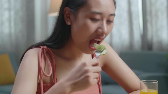Asian Woman With A Dish Of Healthy Food Using A Fork Poking Cucumber Before Eating At Home alt