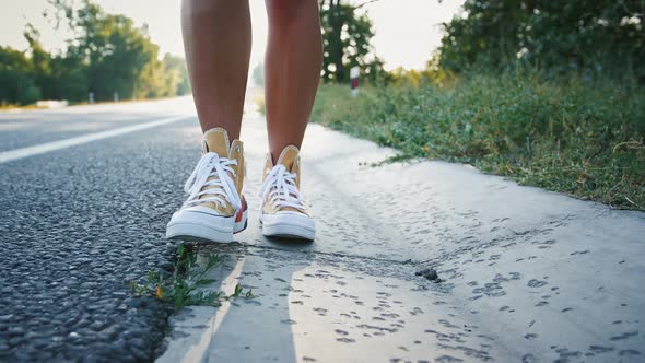 Close Up of Female Legs in Yellow Sneakers Walking Along Road alt