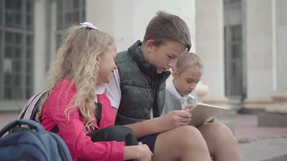 Positive Caucasian Schoolboy Resting with Classmates on School Stairs. Side View of Carefree Boy and alt