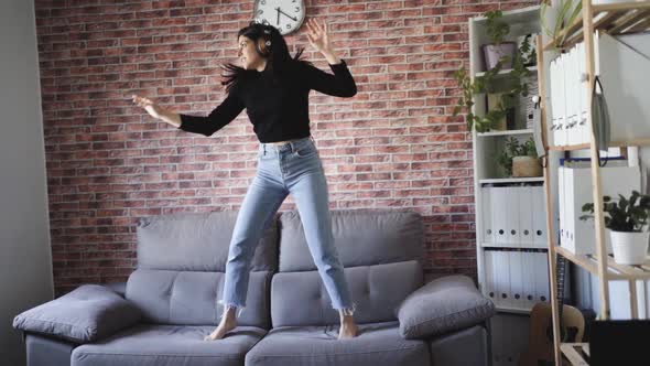 woman dancing on a couch in her house alt