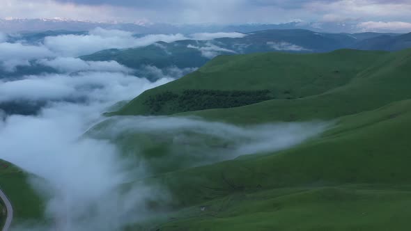 Aerial view on the  green fields at the mountains in the clouds and fog