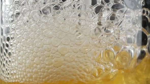 Close up of air bubbles created by someone blowing with straw into full glass of beer or soda