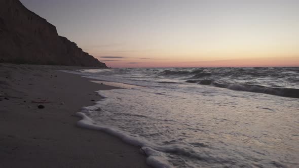 The waves of the ocean roll onto the sandy shore.