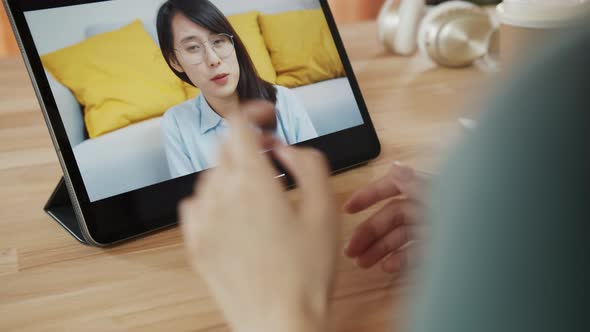 Over the shoulder shot of Asian woman video calling on tablet