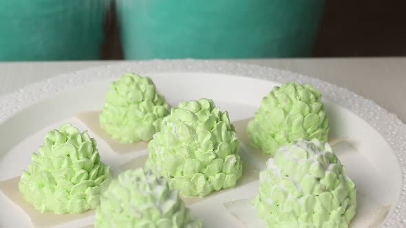A Woman Sprinkles Powdered Sugar On Marshmallow Cones. Light Green Marshmallow Cones. Close Up Shot. alt