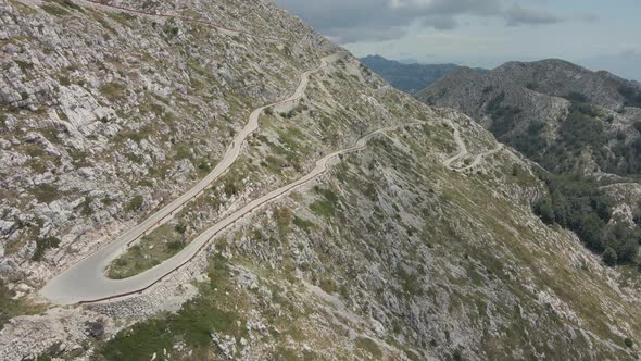 The Cyclist Descends on a Narrow Highway Winding Along the Slope of the Highest Mountain in the