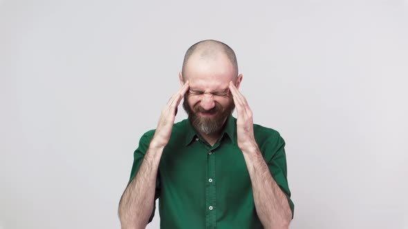 Portrait of bearded man having headache isolated over white background.