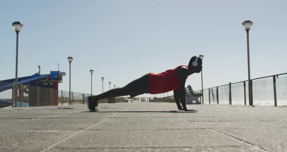 Focused african american man doing press ups, exercising outdoors by the seaside alt