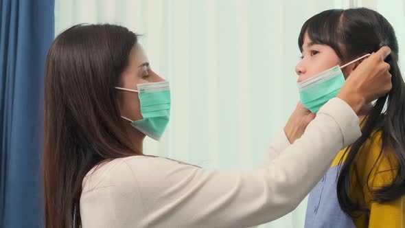 asian mom Putting on a Medical Mask on her daughter with care and tender new norma