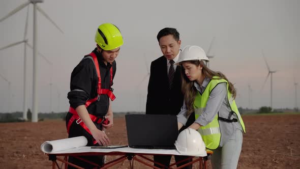 inspector and maintenance engineer with a secretary are inspecting a project in a wind turbine field