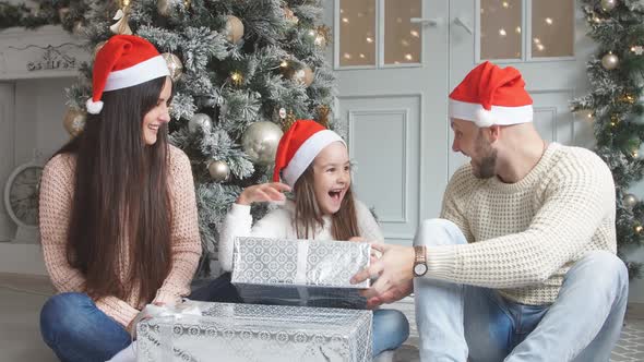 Parents and Young Girl Having Fun Together Near Christmas Tree