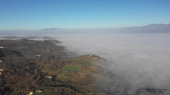 Aerial view of morning fog over forest and village in Umbria, Italy alt