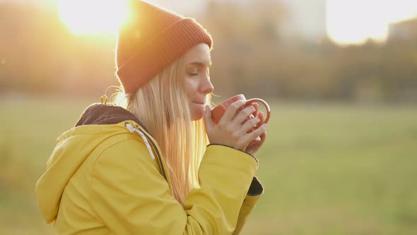 Blonde Woman Drinking Hot Coffee in The Park