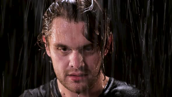 Sad Guy with Long Hair Stands in the Rain at Night and Looks Up at the Camera. Close Up Eyes of Man alt