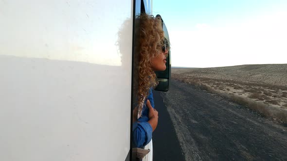 beautiful caucasian young woman travel outside the camper van with wind in the curly hair travel alt