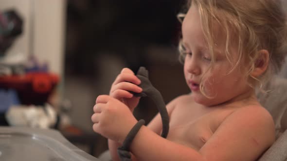 Funny little girl trying to make playdough bracelets alt