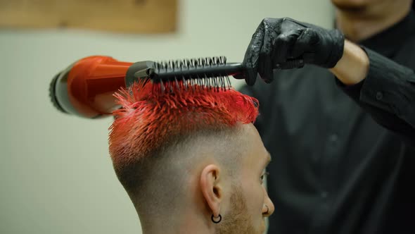 The Hairdresser Blows a Hairdryer and Combs the Guy's Colored Hair alt