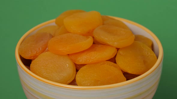 Golden dried apricots in a bowl rotating on a table. Close up view.