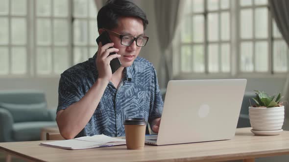 Male Talking On Phone During Work With Laptop Computer At Home alt