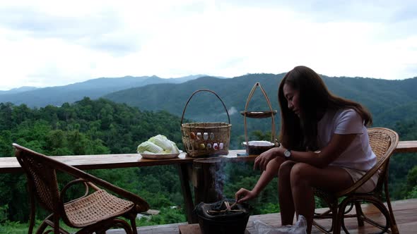 An asian woman preparing and lighting fire in a stove before cooking Moo Kata