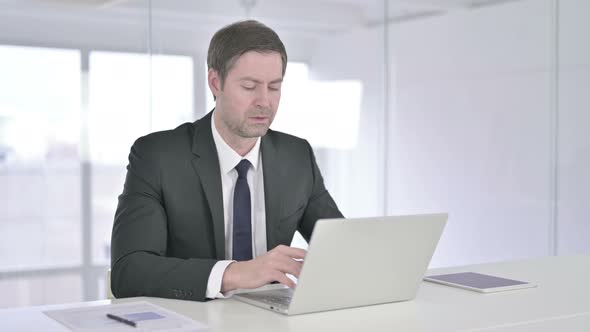 Middle Aged Businessman Doing Thumbs Down in Office  alt