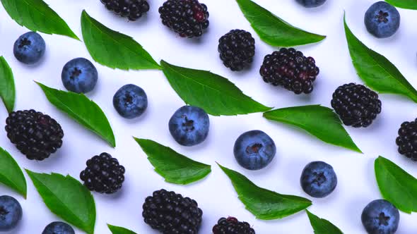 Rotating Blackberries and Blueberries with Leaves on a White Background Closeup Top View