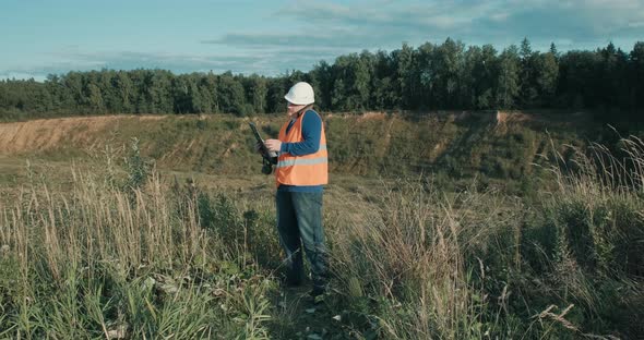 Working Engineer in White Helmet Next to a Sand Pit alt