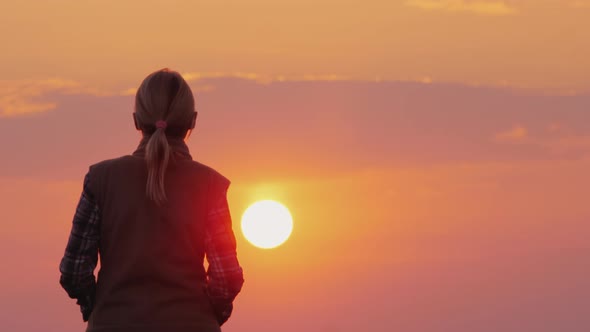 Silhouette of a Middle-aged Woman Who Goes To the Setting Red Sun alt