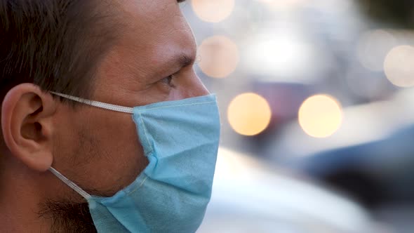 Profile of Young Man Wearing a Disposable Medical Mask on a City Street. Man in Protective Mask on