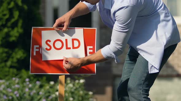 Young Man Setting Sold Sign Front of Building, Property Sell Service, Ownership alt