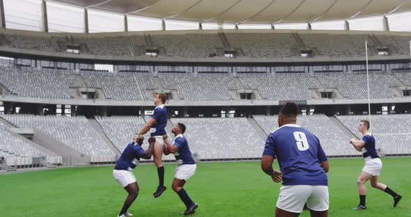 Male rugby players playing rugby match in stadium alt