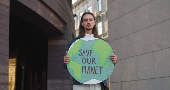 Portrait of Young Male Eco Activist with Earrings Looking To Camera While Standing at Street alt