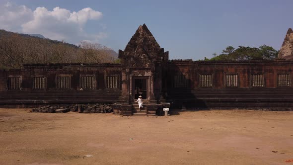 Woman in vietnamese hat go out ancient palace in Wat Phou Khmer Hindu Temple. Architecture Laos Asia