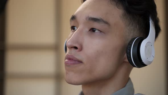 Handsome Asian Guy Enjoys Listening to Music in Headphones alt
