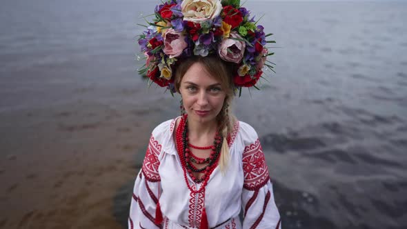 Portrait of Beautiful Ukrainian Woman in Embroidered Dress and Head Wreath Raising Face Looking at alt