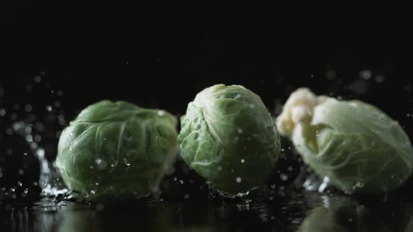 Brussels sprouts falling on water surface. Slow Motion. alt