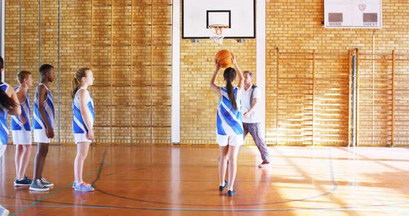 Coach mentoring high school kids In basketball court 4k alt