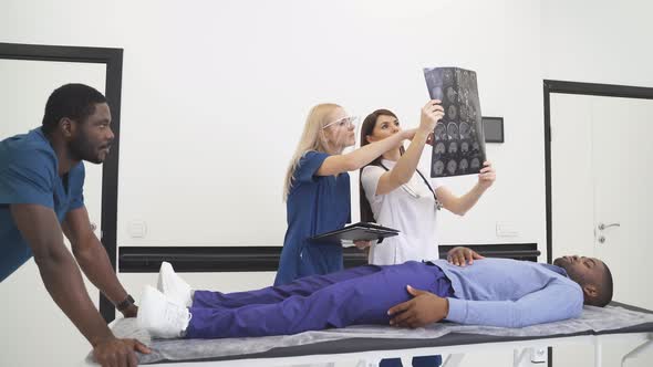 Multiracial Doctor Surgeons Examining Xray Film of Patient Head for Brain Skull Injury Emergency