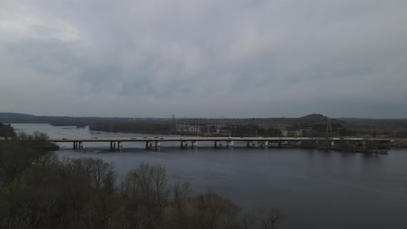 Autumn view of bridge over river in autumn. Utility towers seen on the other side of water.