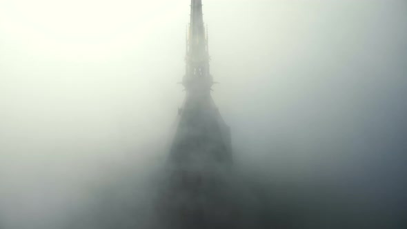 Drone Rising Above Foggy Clouds To Reveal Epic Golden Statue on Top of Iconic Mont Saint Michel alt