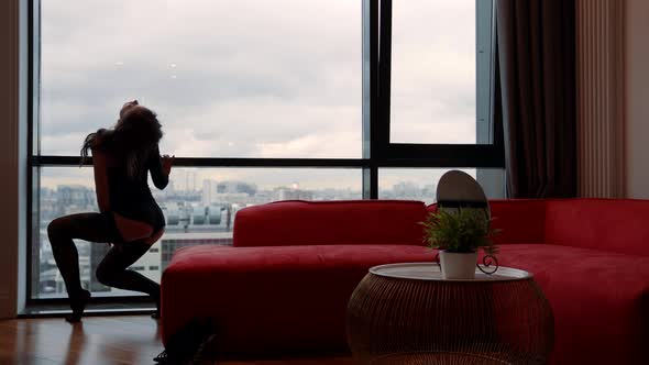 Alluring Sexy Lady Dressed Erotic Suit and Stockings is Dancing Near Window in Apartment Rear View alt