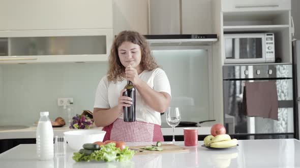 Portrait of Positive Chubby Woman Opening Wine Bottle, Smelling Beverage, and Pouring Alcohol in alt