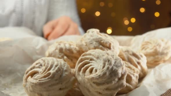 Hand Takes Meringue Cookies From a Baking Sheet alt
