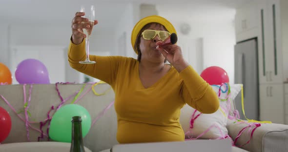 Happy african american senior woman raising champagne glass making new year's eve laptop video call alt
