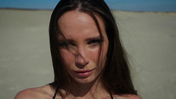 A Beautiful Girl Stands on a Sandy Beach and Sexy Looks Straight Into the Camera