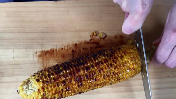 a Japanese female chef cuts corn on cutting board at her home kitchen, Tokyo, Japan. July 2019. Came alt