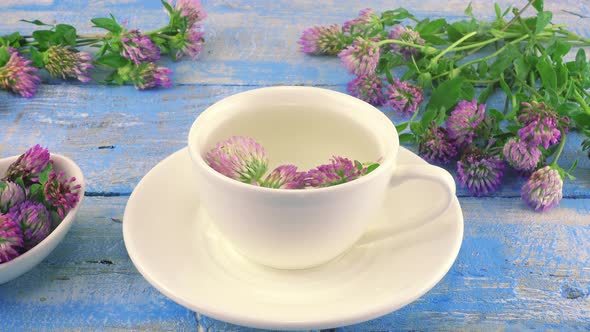 Brewing a tisanes from red clover in a white cup.  alt
